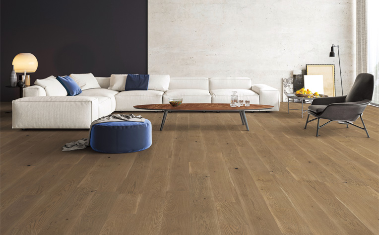 warm toned hardwood flooring in living room with large white couch and blue decor.